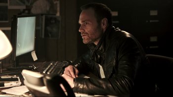 Movie still from “Hellraiser: Judgment” (2018), directed by Gary J. Tunnicliffe – A man sitting at a table with a keyboard; Close Up shot, Low angle