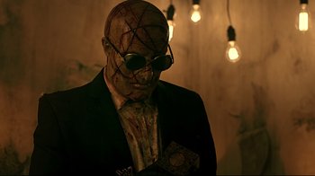 Movie still from “Hellraiser: Judgment” (2018), directed by Gary J. Tunnicliffe – A man in a suit and tie wearing a mask; Medium shot, Low angle