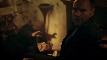 Movie still from “Hellraiser: Judgment” (2018), directed by Gary J. Tunnicliffe – A man sitting in front of another man with a beard; Medium shot, Over the shoulder angle