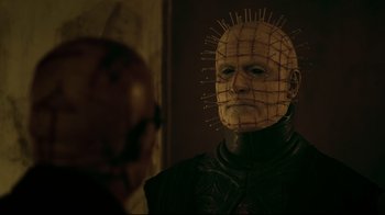Movie still from “Hellraiser: Judgment” (2018), directed by Gary J. Tunnicliffe – A man with a pinhead mask in a room; Close Up shot, Over the shoulder angle