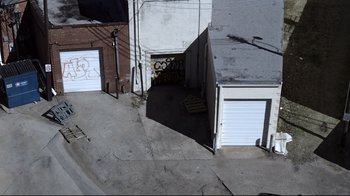 Movie still from “Hellraiser: Judgment” (2018), directed by Gary J. Tunnicliffe – An aerial view of a garage with graffiti on the side; Extreme Wide shot, Overhead angle
