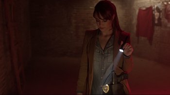 Movie still from “Hellraiser: Judgment” (2018), directed by Gary J. Tunnicliffe – A woman is holding a flashlight in a dark room; Medium shot, Over the shoulder angle