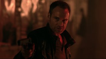Movie still from “Hellraiser: Judgment” (2018), directed by Gary J. Tunnicliffe – A man in a leather jacket holding a gun; Close Up shot, Over the shoulder angle