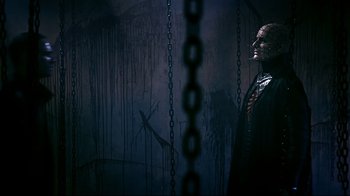 Movie still from “Hellraiser: Judgment” (2018), directed by Gary J. Tunnicliffe – A man in a suit and tie standing next to chains; Medium shot, Low angle