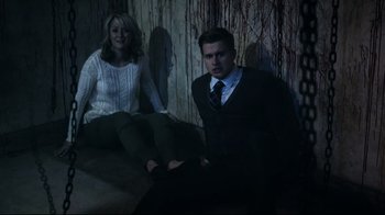 Movie still from “Hellraiser: Judgment” (2018), directed by Gary J. Tunnicliffe – A man and a woman sitting on a bed in a room; Medium shot, High angle