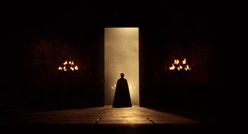 Movie still from “Henry V” (1989), directed by Kenneth Branagh – A man standing in front of a doorway with candles; Extreme Wide shot, Low angle