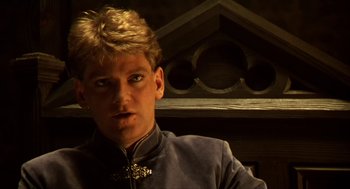 Movie still from “Henry V” (1989), directed by Kenneth Branagh – A man with blonde spiky hair wearing a blue jacket; Close Up shot, Low angle