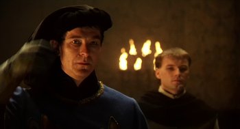 Movie still from “Henry V” (1989), directed by Kenneth Branagh – Two men in medieval garb standing in front of candles; Close Up shot, Over the shoulder angle