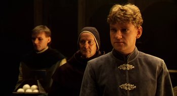 Movie still from “Henry V” (1989), directed by Kenneth Branagh – A group of people standing next to each other in a dark room; Medium shot, Over the shoulder angle