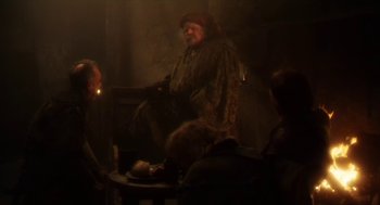 Movie still from “Henry V” (1989), directed by Kenneth Branagh – A man sitting at a table with a cigarette in his mouth; Wide shot, Over the shoulder angle