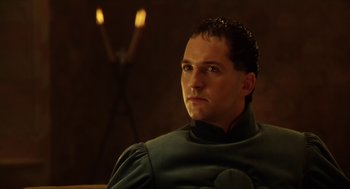 Movie still from “Henry V” (1989), directed by Kenneth Branagh – A man sitting in front of a candle holder; Close Up shot, Low angle