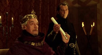 Movie still from “Henry V” (1989), directed by Kenneth Branagh – Two men dressed in medieval garb holding a white object; Medium shot, Low angle