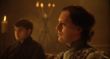 Movie still from “Henry V” (1989), directed by Kenneth Branagh – A man in a dark room with candles in the background; Close Up shot, Low angle