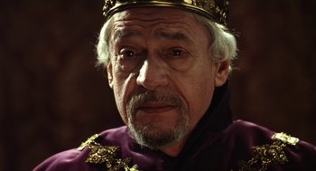 Movie still from “Henry V” (1989), directed by Kenneth Branagh – An older man wearing a purple robe and a gold crown; Close Up shot, Over the shoulder angle