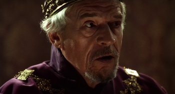 Movie still from “Henry V” (1989), directed by Kenneth Branagh – An old man wearing a crown and a purple robe; Close Up shot, Over the shoulder angle