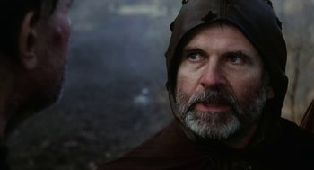 Movie still from “Henry V” (1989), directed by Kenneth Branagh – A man with a gray beard wearing a brown hood; Close Up shot, Over the shoulder angle