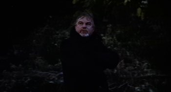 Movie still from “Henry V” (1989), directed by Kenneth Branagh – A man in a black jacket standing next to a tree; Medium shot, Low angle