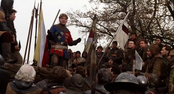 Movie still from “Henry V” (1989), directed by Kenneth Branagh – A crowd of people in medieval garb gathered around a man in medieval garb; Medium shot, Low angle
