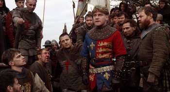Movie still from “Henry V” (1989), directed by Kenneth Branagh – A group of men in medieval garb standing next to each other; Medium shot, Low angle