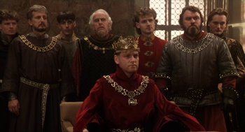 Movie still from “Henry V” (1989), directed by Kenneth Branagh – A group of men in medieval garb standing in front of a wall; Medium shot, High angle