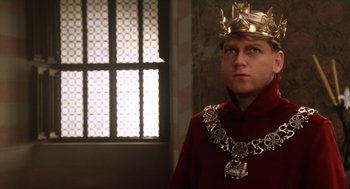 Movie still from “Henry V” (1989), directed by Kenneth Branagh – A man wearing a gold crown and a red robe; Close Up shot, Over the shoulder angle