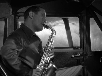 Movie still from “Here Comes Mr. Jordan” (1941), directed by Alexander Hall – A black and white photo of a man playing a saxophone; Medium shot, High angle