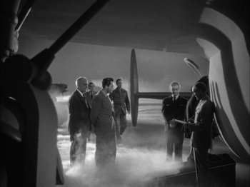 Movie still from “Here Comes Mr. Jordan” (1941), directed by Alexander Hall – A black and white photo of a group of men standing in front of an airplane; Wide shot, High angle