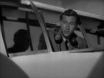 Movie still from “Here Comes Mr. Jordan” (1941), directed by Alexander Hall – A man with headphones looking out of a window of an airplane; Close Up shot, High angle