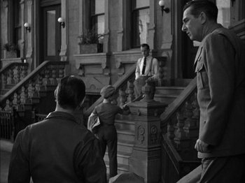 Movie still from “Here Comes Mr. Jordan” (1941), directed by Alexander Hall – A group of men standing on steps in front of a building; Wide shot, Over the shoulder angle