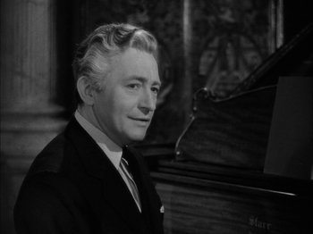 Movie still from “Here Comes Mr. Jordan” (1941), directed by Alexander Hall – An older man in a suit and tie next to a piano; Close Up shot, High angle