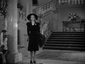 Movie still from “Here Comes Mr. Jordan” (1941), directed by Alexander Hall – A black and white photo of a woman in a black dress and a hat; Wide shot, Low angle