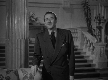 Movie still from “Here Comes Mr. Jordan” (1941), directed by Alexander Hall – A black and white photo of a man in a suit and tie; Medium shot, Low angle