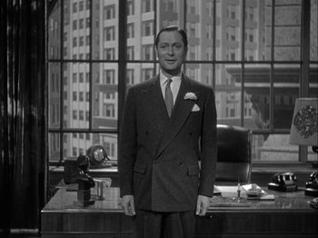 Movie still from “Here Comes Mr. Jordan” (1941), directed by Alexander Hall – A black and white photo of a man in a suit and tie; Medium shot, Low angle