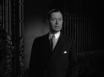 Movie still from “Here Comes Mr. Jordan” (1941), directed by Alexander Hall – A black and white photo of a man in a suit and tie; Medium shot, Low angle
