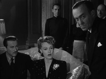 Movie still from “Here Comes Mr. Jordan” (1941), directed by Alexander Hall – A group of people standing around a woman in a room; Medium shot, Over the shoulder angle