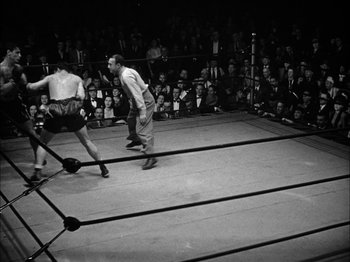 Movie still from “Here Comes Mr. Jordan” (1941), directed by Alexander Hall – Two men in a boxing ring in front of a crowd of people; Wide shot, High angle