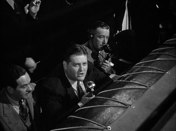 Movie still from “Here Comes Mr. Jordan” (1941), directed by Alexander Hall – A group of men sitting next to each other on a stage; Medium shot, Low angle