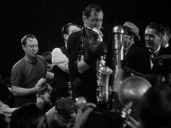 Movie still from “Here Comes Mr. Jordan” (1941), directed by Alexander Hall – A group of men standing around a microphone; Medium shot, High angle