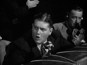 Movie still from “Here Comes Mr. Jordan” (1941), directed by Alexander Hall – A black - and - white photo of a man with a microphone; Close Up shot, High angle