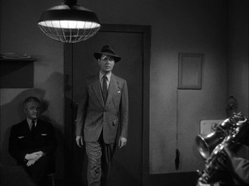 Movie still from “Here Comes Mr. Jordan” (1941), directed by Alexander Hall – A black and white photo of a man in a suit and hat; Medium shot, Low angle