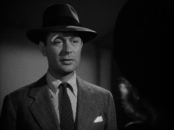 Movie still from “Here Comes Mr. Jordan” (1941), directed by Alexander Hall – A man wearing a suit and hat in a black and white photo; Close Up shot, Over the shoulder angle