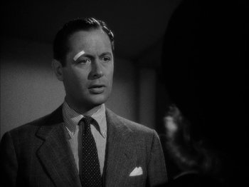 Movie still from “Here Comes Mr. Jordan” (1941), directed by Alexander Hall – A man in a suit and tie with a bandage on his face; Close Up shot, Over the shoulder angle
