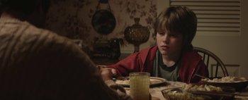 Movie still from “Hesher” (2010), directed by Spencer Susser – A boy sitting at a dinner table with a glass of water; Close Up shot, Over the shoulder angle