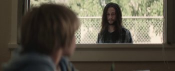 Movie still from “Hesher” (2010), directed by Spencer Susser – A man with long hair looking in the mirror; Medium shot, Over the shoulder angle