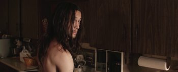 Movie still from “Hesher” (2010), directed by Spencer Susser – A man with long black hair looking at a mirror; Close Up shot, Over the shoulder angle