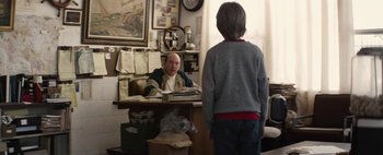 Movie still from “Hesher” (2010), directed by Spencer Susser – A man sitting at a desk with a boy standing in front of him; Medium shot, Over the shoulder angle