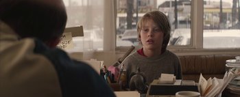 Movie still from “Hesher” (2010), directed by Spencer Susser – A young boy sitting at a table in front of a window; Close Up shot, Over the shoulder angle
