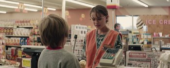 Movie still from “Hesher” (2010), directed by Spencer Susser – A woman in an orange vest talking to a boy in front of a cash register; Medium shot, Over the shoulder angle