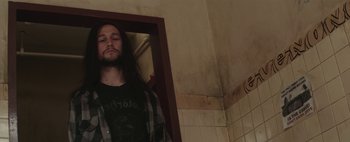 Movie still from “Hesher” (2010), directed by Spencer Susser – A man with long hair standing next to a bathroom mirror; Medium shot, Low angle