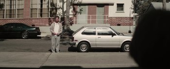 Movie still from “Hesher” (2010), directed by Spencer Susser – A man standing in front of a parked car; Wide shot, High angle